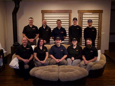 Dealership staff wearing black polo shirts, sitting and standing in a semi circle