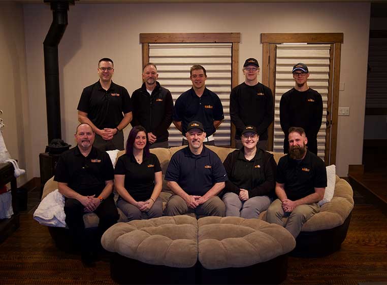 Dealership staff wearing black polo shirts, sitting and standing in a semi circle
